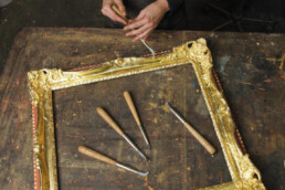 Artisan sculptant un cadre en bois doré à l'or fin