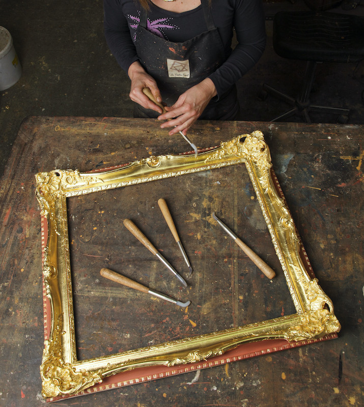 Artisan sculptant un cadre en bois doré à l'or fin